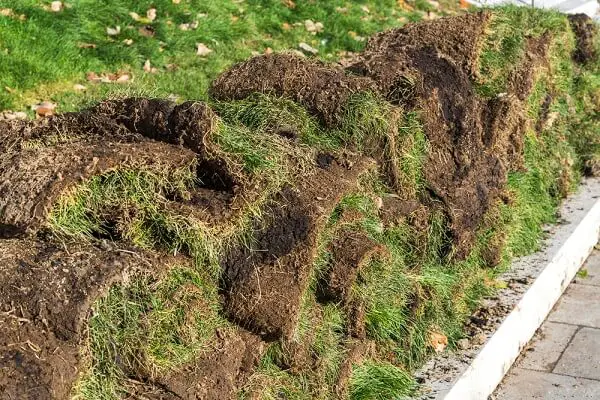 a messy piles of sod stacked on top of each other - tearing out sod for drought tolerant lawn replacement