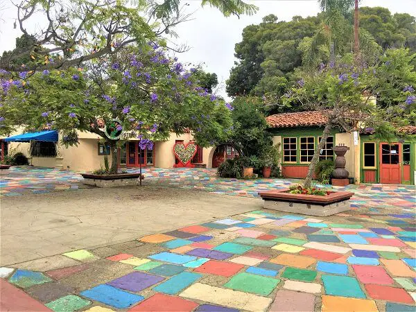 colorful ground tiles and purple blooming jacaranda amid Balboa Park tile roofed art cottages