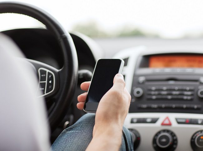 man's hand holding a cell phone in the car while driving in San Diego 