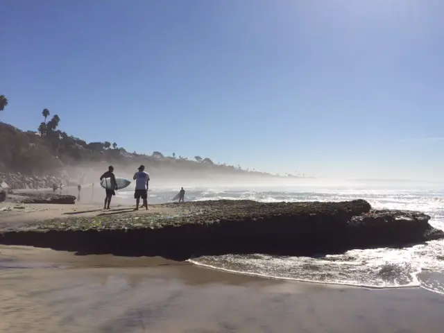 surfer with board standing on rock at Swamis